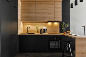 a kitchen with black counters and wooden cabinets at Cracow Palm Apartment in Kraków