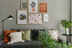 a living room with a gray couch with pillows at Cracow Palm Apartment in Kraków +9 photos