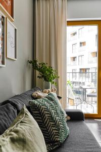 a couch with a teddy bear on it in a room with a window at Cracow Palm Apartment in Kraków