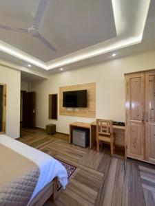 Schlafzimmer mit einem Bett, einem Schreibtisch und einem TV in der Unterkunft Heryk Hillview Hotel in Dharamshala