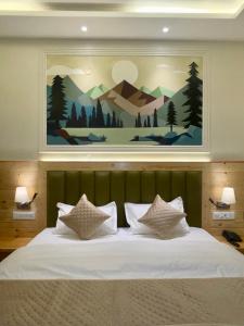 達蘭薩拉的住宿－Heryk Hillview Hotel，一间卧室配有一张大床,上面有画作