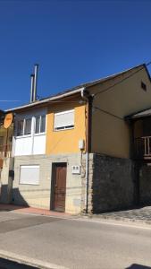 um edifício amarelo e branco com uma porta castanha em La casita del Bierzo em Carracedelo