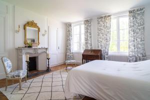 a bedroom with a bed and a fireplace and a mirror at La Prévôté de Grainville - Manoir normand du XVIIIe siècle in Grainville