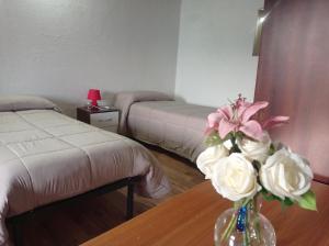 una habitación con 2 camas y un jarrón de flores sobre una mesa en Casa vacanze Casa di Corte, en Adrara San Rocco