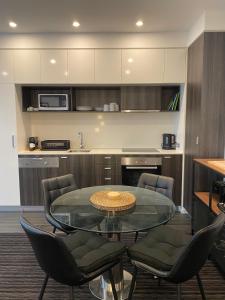 cocina con mesa de cristal y sillas en Modern Quiet 1 & 2 Bed Apt Opposite Albert Park en Melbourne