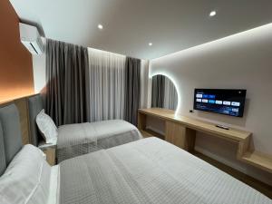 a hotel room with two beds and a flat screen tv at Hotel Lyhnidas in Pogradec