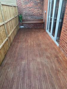 a patio with a wooden floor and a fence at Exclusive Lakeside Apartment in Grays Thurrock