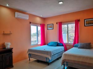 2 camas en una habitación con paredes y ventanas de color naranja en Hotel el Paredon, en El Paredón Buena Vista