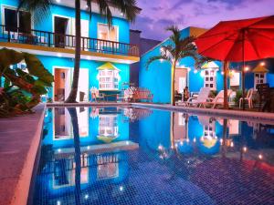 una piscina frente a un edificio azul con una sombrilla roja en Hotel el Paredon en El Paredón Buena Vista