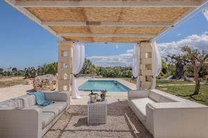 un patio con mobili bianchi e una piscina di Extravacanza Polignano a Mare a Polignano a Mare