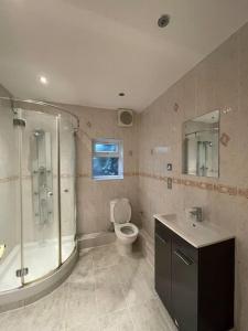 a bathroom with a shower and a toilet and a sink at Modern Spacious 4-Bed House in London