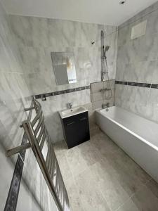 a white bathroom with a tub and a sink at Modern Spacious 4-Bed House in London