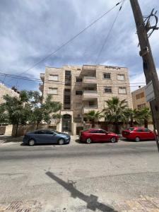 3 voitures garées devant un bâtiment dans l'établissement Comfortable stay, à Amman