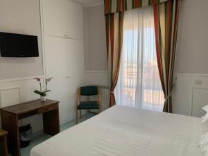 een slaapkamer met een bed, een bureau en een raam bij Hotel Conte in Ischia