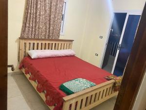 a small bedroom with a wooden bed with a red blanket at شقه مصيف للايجار بكمبوند عجيبه سيتي مرسي مطروح in Zâwyet Umm el Rakham