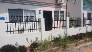 uma casa branca com uma cerca e uma porta preta em Impeccable 1-Bed House in Kweiman Station danfa em Danfa