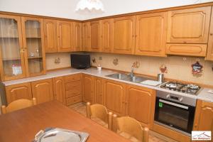 a kitchen with wooden cabinets and a sink and a table at Casa Montegrappa - tra Etna e Mare Parcheggio gratuito in Zafferana Etnea
