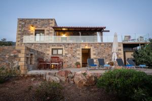 ein Steinhaus mit Stühlen und einem Tisch in der Unterkunft Blue Pearl Villa in AmigdhalokeFálion