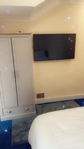 a bedroom with a bed and a tv on the wall at Stay with Chris in Woking
