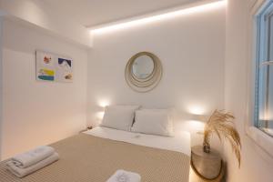 a white bedroom with a bed and a mirror at Hyades - Downtown Suites, Mykonos Town in Mýkonos City