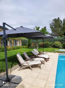 - un parasol et des chaises longues à côté de la piscine dans l'établissement GITE AUX 4 SAISONS DU COLORADO PROVENÇAL - 3 ÉTOILES - Rustrel, à Rustrel