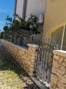 a stone wall with a wrought iron fence at Apartments Annie in Rogoznica