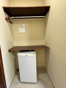 a small refrigerator in a room with a shelf at Werneck Residence Suites in Ubatuba