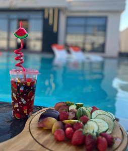 un piatto di frutta e un drink accanto alla piscina di Tixos Farm a Irbid