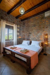 a bedroom with a large bed in a stone wall at Blue Pearl Villa in AmigdhalokeFálion