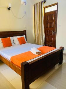 um quarto com uma cama com lençóis laranja e branco em Danmic em Mombasa