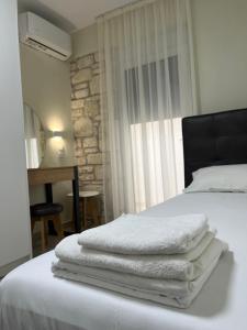 una pila di asciugamani appoggiata sopra un letto di Sun & Stone House a Polykhrono