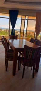 Danmic في مومباسا: طاولة وكراسي خشبية في غرفة بها نوافذ