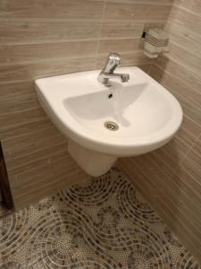 a white sink in a bathroom with a tile floor at Opaque gardens in Tezo