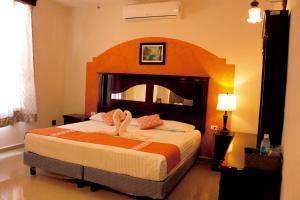 um quarto com uma cama grande e uma grande cabeceira. em Hotel Quinta Marciala MX em Valladolid