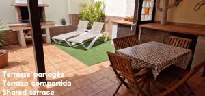 eine Terrasse mit 2 Stühlen, einem Tisch, einem Tisch und Stühlen in der Unterkunft Bedroom with shared bathroom and swimming pool in Corralejo