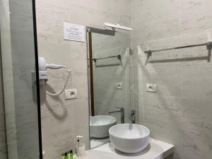 un bagno bianco con lavandino e specchio di Valta Hotel a Qeparo