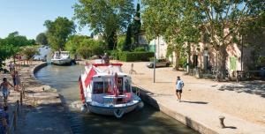 Ein Boot ist in einem Kanal neben einem Bürgersteig angedockt. in der Unterkunft Studio HELTYMIE 4-Vélos bienvenus-parking gratuit in Portiragnes