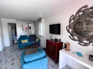 sala de estar con sofá azul y TV en Naturistecapdagde Villa Port Venus Serenity, en Cap d'Agde