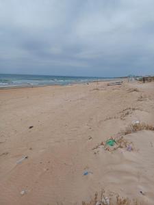 a beach with trash in the sand and the ocean at MAISON DE VACANCE in Mostaganem