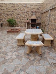 une table de pique-nique et deux bancs sur une terrasse dans l'établissement MAISON DE VACANCE, à Mostaganem