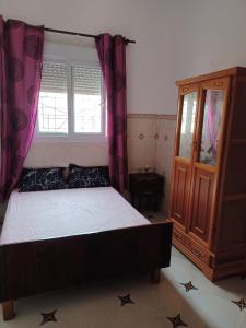 een slaapkamer met een bed, een dressoir en een raam bij MAISON DE VACANCE in Mostaganem