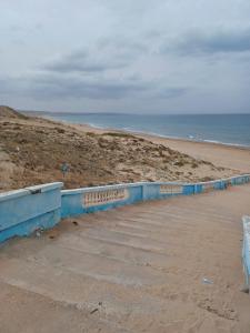 a beach with a blue retaining wall and the ocean at MAISON DE VACANCE in Mostaganem