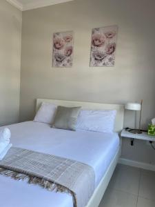a bed in a bedroom with two pictures on the wall at Classy 2 bedroom in Halfway Gardens in Midrand