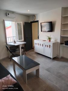 ein Wohnzimmer mit einem Tisch und einem TV in der Unterkunft Studio HELTYMIE 4-Vélos bienvenus-parking gratuit in Portiragnes