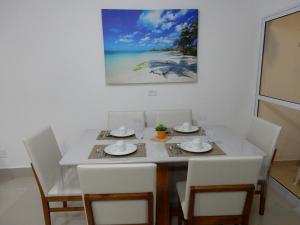 tavolo da pranzo con sedie bianche e un quadro di Casa sobrado 7 a Guarujá