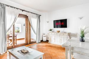 un soggiorno con tv e tavolo di PORTO CERVO-CALA DEL FARO [Parking-Sea-Garden] a Porto Cervo