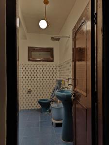 a bathroom with a blue sink and a toilet at The Kailasha Homestay in Nagar