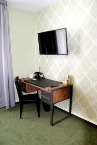 a desk with a television on a wall with a chair at Spielzeughotel Sonneberg in Sonneberg