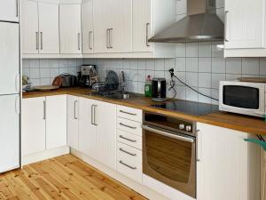 uma cozinha com armários brancos e um micro-ondas em Holiday home STENSJÖN em Boda