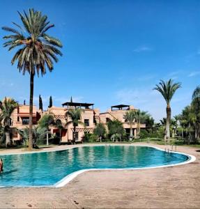 uma piscina em frente a um resort com palmeiras em La Perle de l'Atlas by Golf Resort em Marraquexe